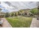 Expansive backyard with a large grassy area, stone retaining wall, and mountain views at 5879 Sky Heights Ct, Las Vegas, NV 89135