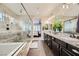 A view of the bathroom that shows granite counters with double sinks, a glass shower, and a view of the main bedroom at 5879 Sky Heights Ct, Las Vegas, NV 89135
