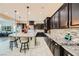 Gourmet kitchen featuring dark wood cabinetry, granite countertops, stylish barstool seating, and sleek backsplash at 5879 Sky Heights Ct, Las Vegas, NV 89135