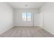 An airy bedroom featuring neutral carpet, a window with blinds, and a white door at 6737 Lotus Vista Ct, Las Vegas, NV 89156