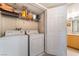 Bright laundry room featuring a washer, dryer, and storage shelves, conveniently located near the bathroom at 6955 N Durango Dr # 3013, Las Vegas, NV 89149