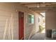 This home features beige siding, a red door, and a covered walkway at 704 Kings Ave, North Las Vegas, NV 89030