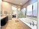 Bathroom featuring a soaking tub and glass-enclosed shower with tile flooring at 10719 Hammett Park Ave, Las Vegas, NV 89166
