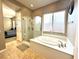 Bathroom featuring a soaking tub and glass-enclosed shower with tile flooring at 10719 Hammett Park Ave, Las Vegas, NV 89166