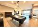 Open-concept living room with a pool table, piano, and seamless flow to the kitchen at 10719 Hammett Park Ave, Las Vegas, NV 89166