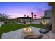 Spacious backyard with a built-in fire pit, dining area, and artificial turf at 12637 Penfield Ave, Las Vegas, NV 89138