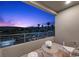 Balcony with seating overlooking palm trees and distant mountains during a twilight sky at 12637 Penfield Ave, Las Vegas, NV 89138