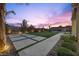 Beautiful backyard with putting green, stone walkways, and landscape lighting at twilight at 13 Scenic Terrain Ave, Henderson, NV 89011