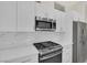 Close-up of kitchen showcasing white cabinets, stainless steel appliances, and stone backsplash at 2367 Tilden Way, Henderson, NV 89074