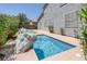 This backyard has a pool with rock decor, a concrete patio, and mature landscaping near the house at 2367 Tilden Way, Henderson, NV 89074