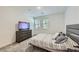 Well-lit bedroom with striped bedding, two windows, and a wooden dresser with flatscreen TV at 2555 Hampton Rd # 2108, Henderson, NV 89052