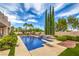 Sparkling pool and spa surrounded by lush greenery, palm trees, and clear blue skies at 2982 Hammerwood Dr, Las Vegas, NV 89135