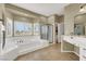Bright bathroom with a large tub, glass enclosed shower, and dual sinks with white cabinetry at 3204 Rutledge Dr, Las Vegas, NV 89120