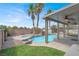Inviting backyard pool featuring a rock waterfall, palm trees, and a covered patio at 3204 Rutledge Dr, Las Vegas, NV 89120