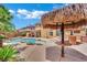 Lush backyard showcasing a tiki hut, outdoor kitchen, sparkling pool, and relaxing patio area at 4139 Abernethy Forest Pl, Las Vegas, NV 89141
