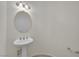 A pedestal sink and oval mirror are illuminated by a sconce in this bathroom at 4139 Abernethy Forest Pl, Las Vegas, NV 89141