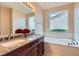 Bright bathroom features dual sinks, dark wood cabinets, and a soaking tub at 4311 Fiore Bella Blvd, Las Vegas, NV 89135