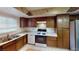 Traditional kitchen featuring tile countertops, brown wooden cabinets, stainless steel sink and white appliances at 4998 Schumann Dr, Las Vegas, NV 89146