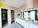 Well-lit primary bathroom with dual sinks, framed mirrors, white cabinets and a walk in closet at 6021 Vivanco St, North Las Vegas, NV 89081