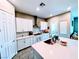 Bright kitchen features white cabinets, a stylish range hood, and a central island with sink at 6021 Vivanco St, North Las Vegas, NV 89081