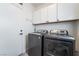 Laundry room with front load washer and dryer and white cabinets for storage at 632 Monument Point St, Henderson, NV 89002