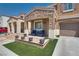 Inviting front porch with stone accents, complemented by artificial turf and desert landscaping, and a two-car garage at 7694 Hampton Park Ln, Las Vegas, NV 89113