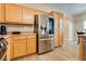 Charming kitchen with stainless steel refrigerator, oak cabinets, and tile flooring that seamlessly connects to dining area at 7694 Hampton Park Ln, Las Vegas, NV 89113