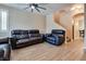 Living room features tile flooring, ceiling fan, dark leather furniture, and staircase at 7694 Hampton Park Ln, Las Vegas, NV 89113