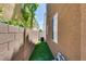 Narrow side yard with artificial turf, brick wall, and room for outdoor storage at 7694 Hampton Park Ln, Las Vegas, NV 89113