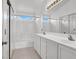 Bright bathroom featuring double sinks, tiled floors, shower, and large vanity mirror at 8389 Charlton Valley Ct, Las Vegas, NV 89123