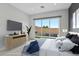 Light-filled bedroom with a large window overlooking the backyard, modern furniture, and an entertainment center at 8956 Skye Treeline St, Las Vegas, NV 89166