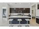 Stylish kitchen featuring a spacious island with bar seating, dark cabinetry, and modern fixtures at 8956 Skye Treeline St, Las Vegas, NV 89166
