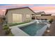 Stunning backyard oasis featuring a pool, spa, waterfall, and outdoor living space at sunset at 8956 Skye Treeline St, Las Vegas, NV 89166