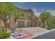 Beautiful two-story home with a stone accent, manicured landscaping, and brick paved driveway and three-car garage at 9792 Crescent Lodge Ct, Las Vegas, NV 89178