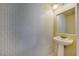 Cozy powder room featuring tiled wall, stylish pedestal sink, and modern light fixture at 9792 Crescent Lodge Ct, Las Vegas, NV 89178