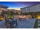 Inviting backyard features a stone fire pit, seating, lush greenery, and ambient lighting perfect for relaxation at 10300 Stroma Ave, Las Vegas, NV 89166