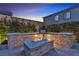 Cozy backyard featuring a stone fire pit, built-in seating, and lush greenery under a vibrant evening sky at 10300 Stroma Ave, Las Vegas, NV 89166