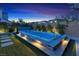 Relaxing backyard featuring a swim spa surrounded by lush greenery and stone accents under a colorful sunset at 10300 Stroma Ave, Las Vegas, NV 89166