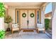 Inviting front porch with neutral colored double doors, decorative wreaths, and two chairs either side at 1235 Panini Dr, Henderson, NV 89052