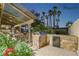 An outdoor kitchen features a stone-clad grill, refrigerator, and counter space, framed by blooming flowers at 1251 Los Meadows Dr, Las Vegas, NV 89110