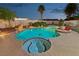 Inviting swimming pool and hot tub with a tiled edge, enhanced by palm trees and stylish landscape lighting at 1251 Los Meadows Dr, Las Vegas, NV 89110