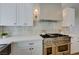 Bright white kitchen with stainless range and hood, quartz countertops and decorative lighting at 1624 Ravanusa Dr, Henderson, NV 89052