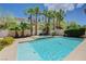 Sparkling pool surrounded by lush landscaping, including palm trees at 1624 Ravanusa Dr, Henderson, NV 89052