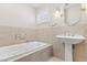 Bright bathroom featuring a deep soaking tub, pedestal sink, tiled walls, and window with shutters at 1912 Parkchester Dr, Las Vegas, NV 89108