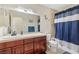 Bathroom featuring wood cabinets, tile backsplash and floors, and shower with blue shower curtain at 1912 Parkchester Dr, Las Vegas, NV 89108