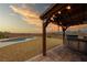 Outdoor kitchen and BBQ under a pergola overlooking the pool at sunset at 2020 S Omaha Ave, Pahrump, NV 89048