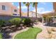 Landscaped backyard with small patch of artificial turf, covered patio, and view of adjacent homes at 203 Sea Rim Ave, Las Vegas, NV 89148