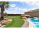 Lush backyard with a custom pool, rock waterfall, green lawn, and mature palm tree at 2181 E Winery Rd, Pahrump, NV 89048