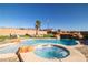 An inviting backyard oasis featuring a rock waterfall, pool, and spa, surrounded by lush landscaping at 2181 E Winery Rd, Pahrump, NV 89048