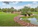 Lush backyard with a pond, complete with a stone-lined edge, greenery, and mature trees offering a tranquil retreat at 3201 Beacon Shores Cir, Las Vegas, NV 89117